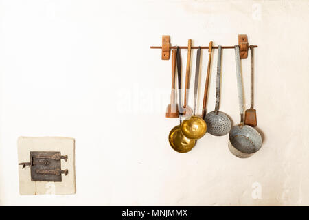 Retro style set of different wooden and metal kitchen spoons and tools hanging on a wall Stock Photo