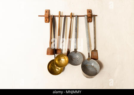 Retro style set of different wooden and metal kitchen spoons and tools hanging on a wall Stock Photo