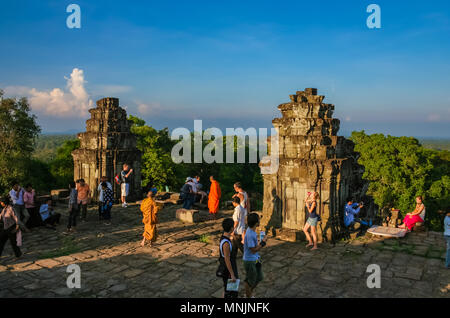 Tourists waiting at the stone towers on the upper terrace of the pyramid shaped Phnom Bakheng temple to view the panoramic sunset. Stock Photo