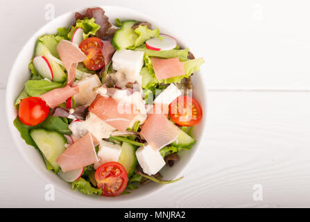 salad with cheese, lettuce, tomato, radish, onion,cucumber in a bowl isolated on a white background. Stock Photo