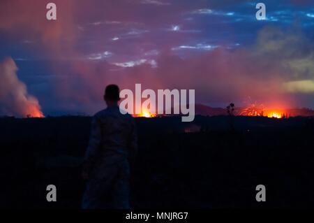 A Hawaii Air National Guard Airman observes three volcanic fissures spewing lava and poison gas into the evening sky from the eruption of the Kilauea volcano May 15, 2018 in Pahoa, Hawaii. The recent eruption continues destroying homes, forcing evacuations and spewing lava and poison gas on the Big Island of Hawaii.