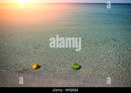 melon and watermelon lies on the beach in the water. Stock Photo