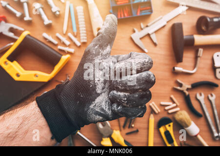 Repairman showing OK thumb up approval hand sign over the work desk with DIY tools, top view Stock Photo