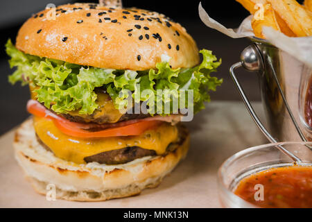 Burger with fried potatoes and tomato sauce on a wooden stand Stock Photo