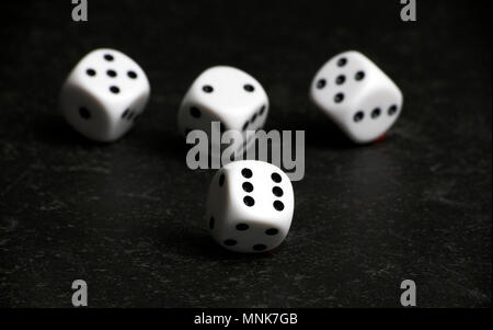 Four white and black dice on a black table Stock Photo