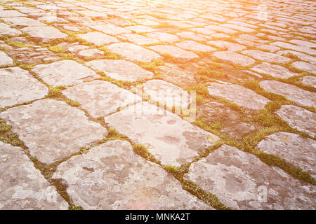 Surface of the old paving stone road with sprouted moss between the stones, natural texture, copy space, toned Stock Photo