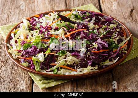 Mix salad of white and red cabbage with carrots, onions, herbs with olive oil close-up on a plate on a table. horizontal Stock Photo