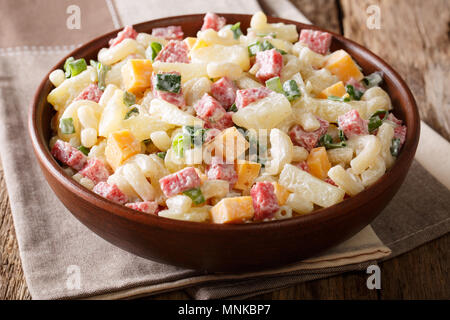 Hawaiian cuisine: salad with pasta, ham, pineapple, onion, cheddar cheese with mayonnaise close-up in a bowl on the table. horizontal, rustic style Stock Photo