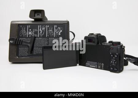 1975 Polaroid Colour Swinger Camera next to a modern Canon PowerShot G5 X Camera Stock Photo