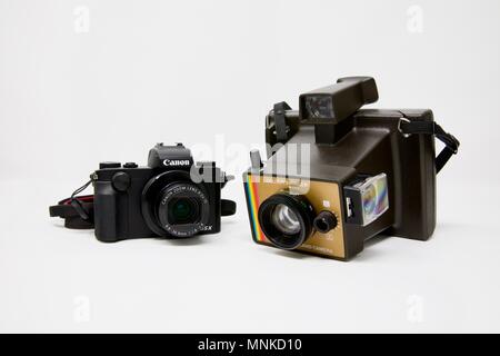 1975 Polaroid Colour Swinger Camera next to a modern Canon PowerShot G5 X Camera Stock Photo