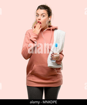 Young sport woman wearing workout sweatshirt covers mouth in shock, looks shy, expressing silence and mistake concepts, scared Stock Photo