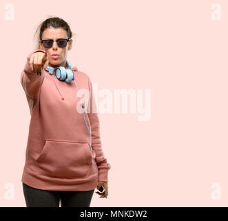 Young sport woman with headphones and sunglasses covers mouth in shock, looks shy, expressing silence and mistake concepts, scared Stock Photo