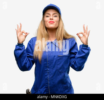 Young plumber woman doing ok sign gesture with both hands expressing meditation and relaxation Stock Photo