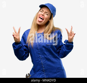 Young plumber woman looking at camera showing tong and making victory sign with fingers Stock Photo