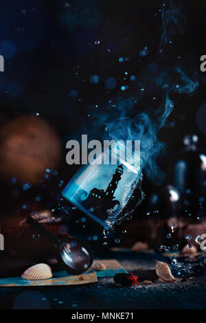 Lighthouse in a glass jar fwith mist, water splashes, compass, globe and seashells on a dark background with smoke. Marine concept with copy space. Ca Stock Photo