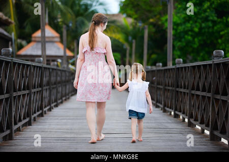 Back view of mother and daughter walking along wooden jetty Stock Photo
