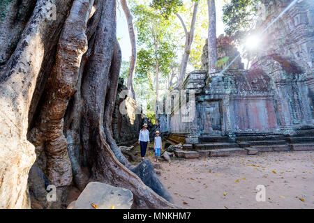 Family visiting ancient Ta Prohm temple in Angkor Archaeological area in Cambodia Stock Photo