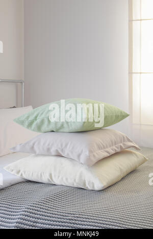 Stack of pastel color pillows on stripe blanket on bed Stock Photo
