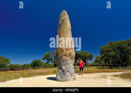 Woman looking to a huge megalithic standing stone Stock Photo