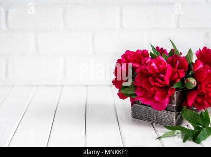 Beautiful pink red marsala peony flowers in wood box on rustic wooden table with copy space for your text. Stock Photo