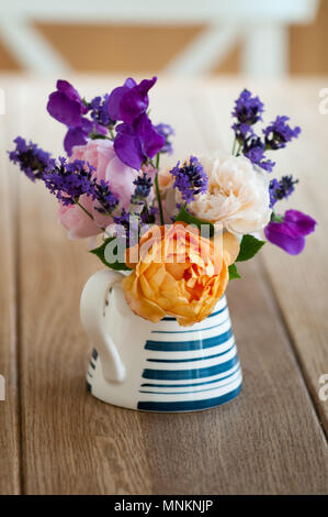Summer flowers in a blue and white jug on a kitchen table Stock Photo