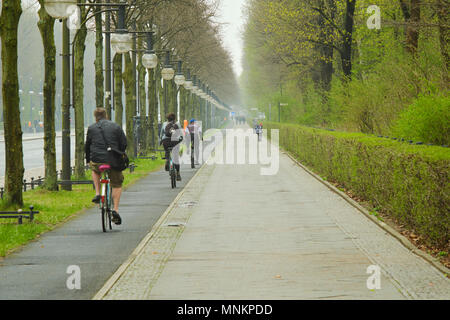 Berlin, Germany - April 14, 2018: Bicycle lane with bicyclists and sidewalk along 17th of June Street and Rose garden im Tiergarten, Berlin Stock Photo