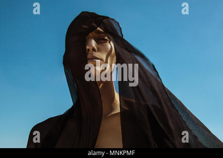 Guy with black scarf and wind on sky background in dessert Stock Photo
