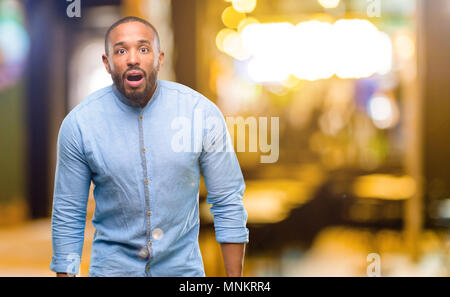 African american man with beard scared in shock, expressing panic and fear at night Stock Photo