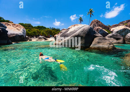 Young woman snorkeling in turquoise tropical water among huge granite boulders at The Baths beach area, British Virgin Islands, Caribbean
