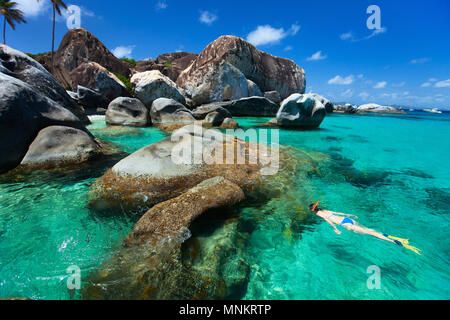 Young woman snorkeling in turquoise tropical water among huge granite boulders at The Baths beach area, British Virgin Islands, Caribbean