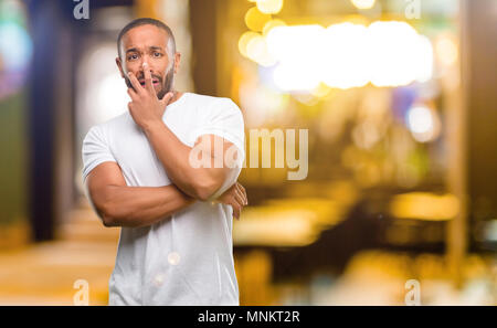 African american man with beard scared in shock, expressing panic and fear at night Stock Photo