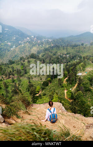 Young woman enjoying breathtaking views over mountains and tea plantations from Little Adams peak in Ella Sri Lanka Stock Photo