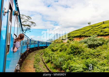 Young woman enjoying train ride from Ella  to Kandy among tea plantations in the highlands of Sri Lanka Stock Photo