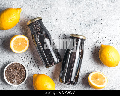 Detox activated charcoal black chia water or lemonade with lemon. Two bottle with black chia infused water. Detox drink idea and recipe. Vegan food and drink. Top view. Copy space for text. Stock Photo