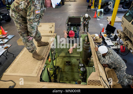 Herbert Green (center), maintenance instructor for the 99th Readiness Division, directs U.S. Army Reserve mechanics from the 200th Military Police Command how the engine pack will go back into an M1117 Armored Security Vehicle (ASV) during a maintenance course hosted in Schenectady, New York, March 14, 2018. This is the first maintenance course in the U.S. Army Reserve designed specifically for the ASV, which has hydraulic components and maintenance procedures that are unlike most other Army vehicles. The ASV is designed to resist the impact of roadside bombs while operating in urban environme Stock Photo