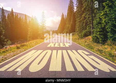 Keep moving text written on road in the mountains Stock Photo
