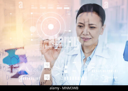 Attentive doctor holding a marker and smiling while writing on the board Stock Photo