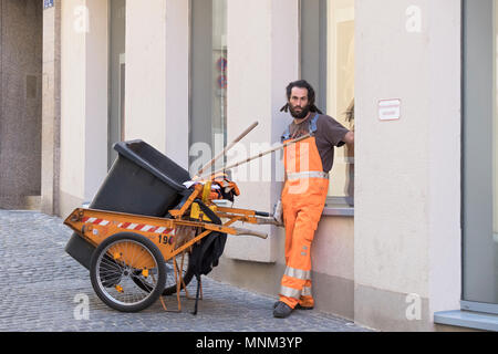 A sanitation man in a  reflective uniform takes a break in Regensburg, Germany. Stock Photo
