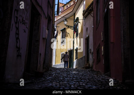 A woman walks through an Alfama alleyway in Lisbon, Portugal. Stock Photo