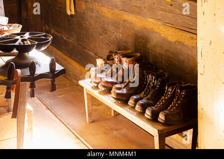 View into a small traditional shoemaker workshop with craft tools, equipment, materials and finished pairs of heavy leather shoes Stock Photo