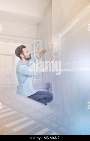 Young man carefully touching a security system while being in smart house Stock Photo