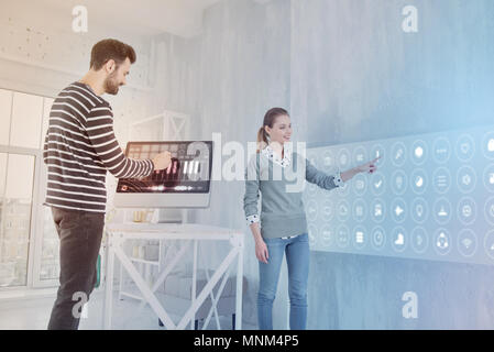 Cheerful programmer working on computer while his coworker standing near Stock Photo