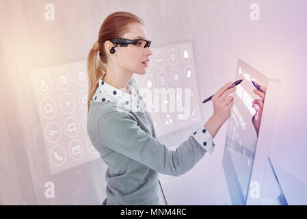 Attentive programmer using a stylus while working on her computer Stock Photo