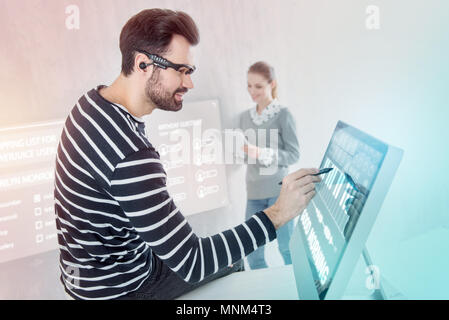 Calm programmer sitting on the table and working in his computer Stock Photo