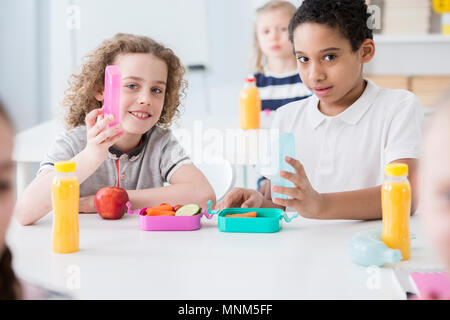 African-american boy and his friend eating fruits during lunch break at school Stock Photo