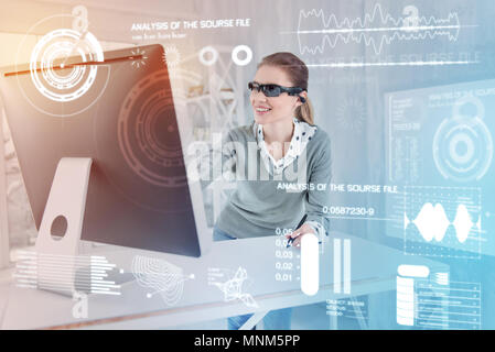 Positive designer smiling while looking at the screen of her convenient computer Stock Photo
