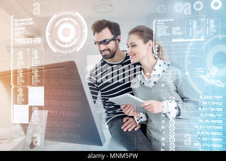 Cheerful programmers looking at the screen of their computer and feeling glad Stock Photo