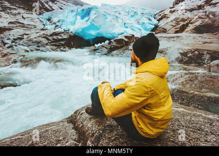 Man traveler relaxing alone travel adventure lifestyle vacations outdoor exploring Norway Nigardsbreen glacier view Stock Photo