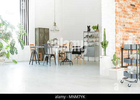 Bright loft interior with communal table, chairs and brick wall Stock Photo