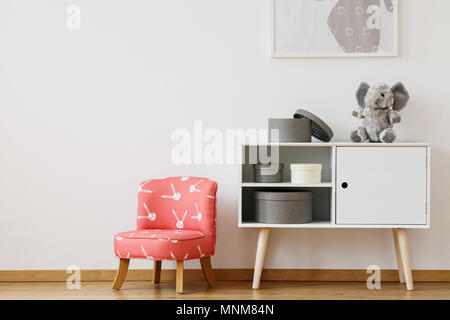 Small cute red chair with rabbits pattern and stuffed fluffy elephant Stock Photo
